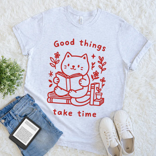 Cute graphic tee featuring reading cat and floral accents on ash grey t-shirt