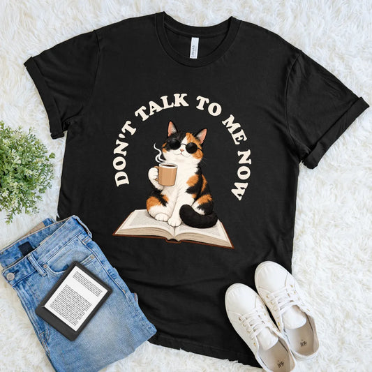 Black funny cat and book lover tee featuring an unbothered calico reader with steaming coffee and playful typography
