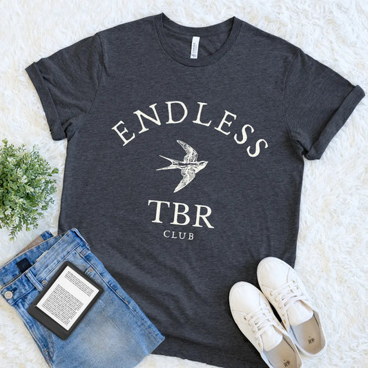 Cozy book lover T-shirt with minimalist TBR club graphic and classic serif typography on dark grey heather fabric