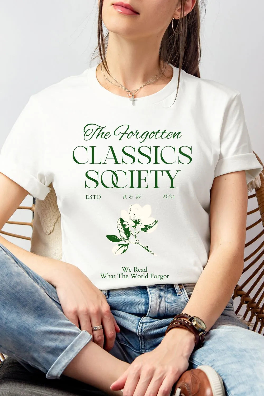 Woman wearing white soft cotton t-shirt featuring "Forgotten Classics Society" in elegant typography and a vintage botanical illustration, styled with denim for relaxed academia look