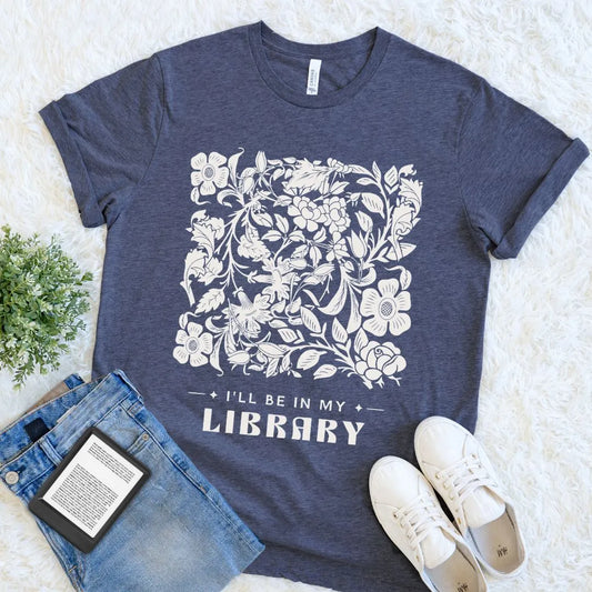 Heather navy “I’ll Be in My Library” reader T-shirt featuring floral artwork and literary typography, a cozy bookish tee for introverts and library lovers.