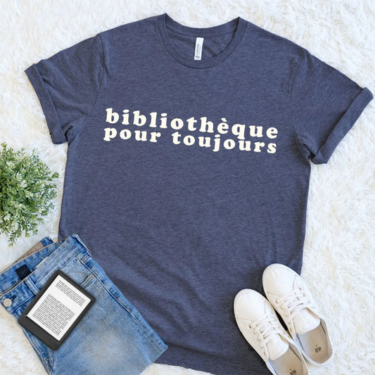 Heather navy French library lover shirt featuring cream retro lettering, arranged with denim, sneakers, and a digital book