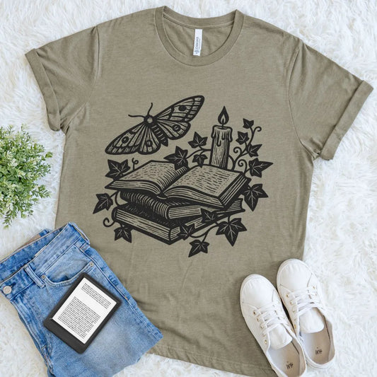 Dark academia reader shirt featuring stacked books, butterfly moth, and candle design on heather olive fabric