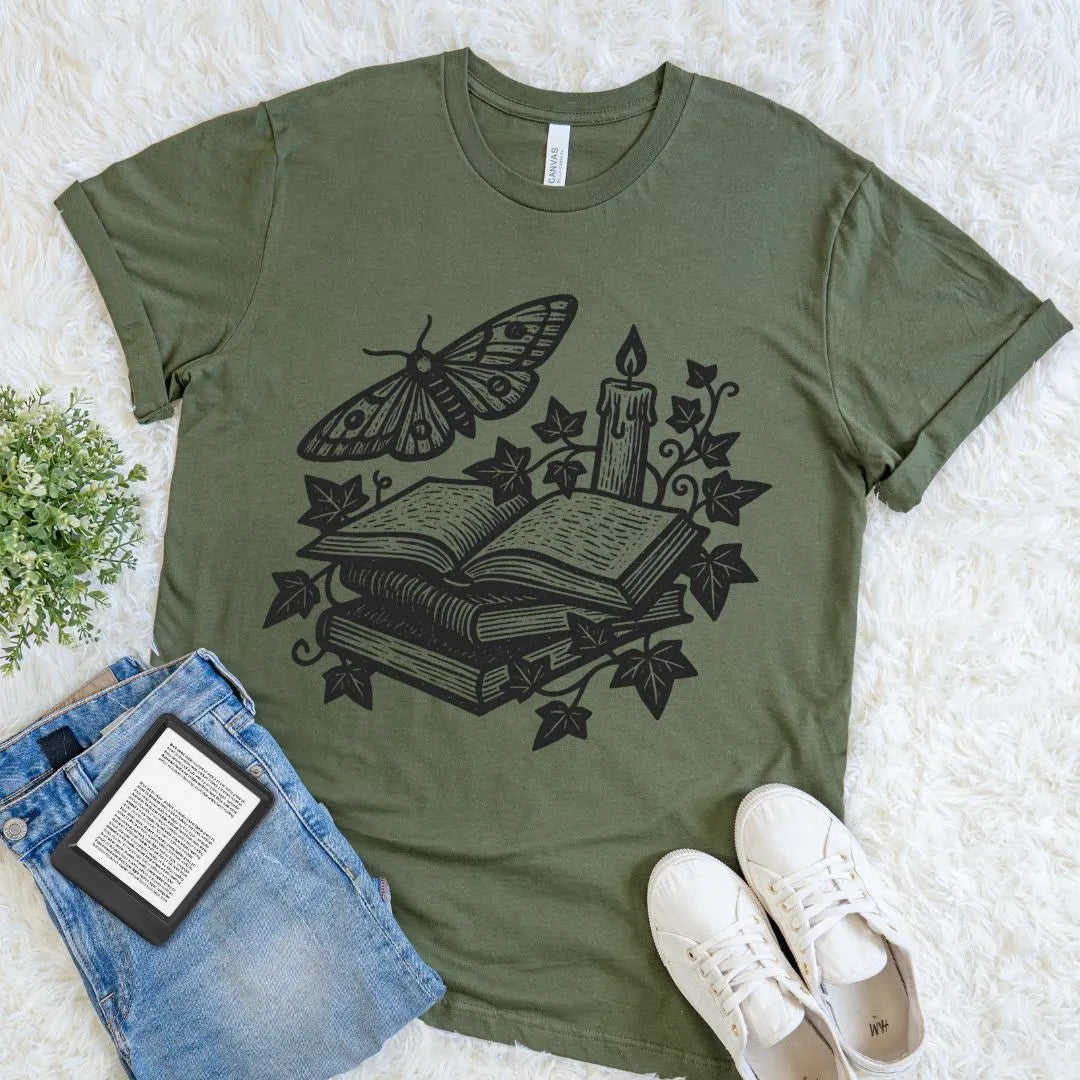Dark academia aesthetic reading themed T-shirt with gothic book stack, candle, and moth illustration on military green fabric