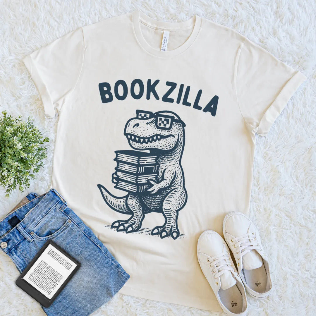 Beige humorous bookish tee with a retro-style dinosaur and reading theme