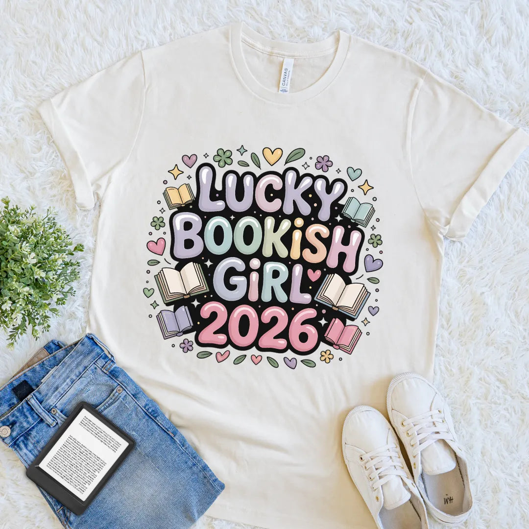 Flat lay of cream soft cotton T-shirt with pastel โLucky Bookish Girl 2026โ design