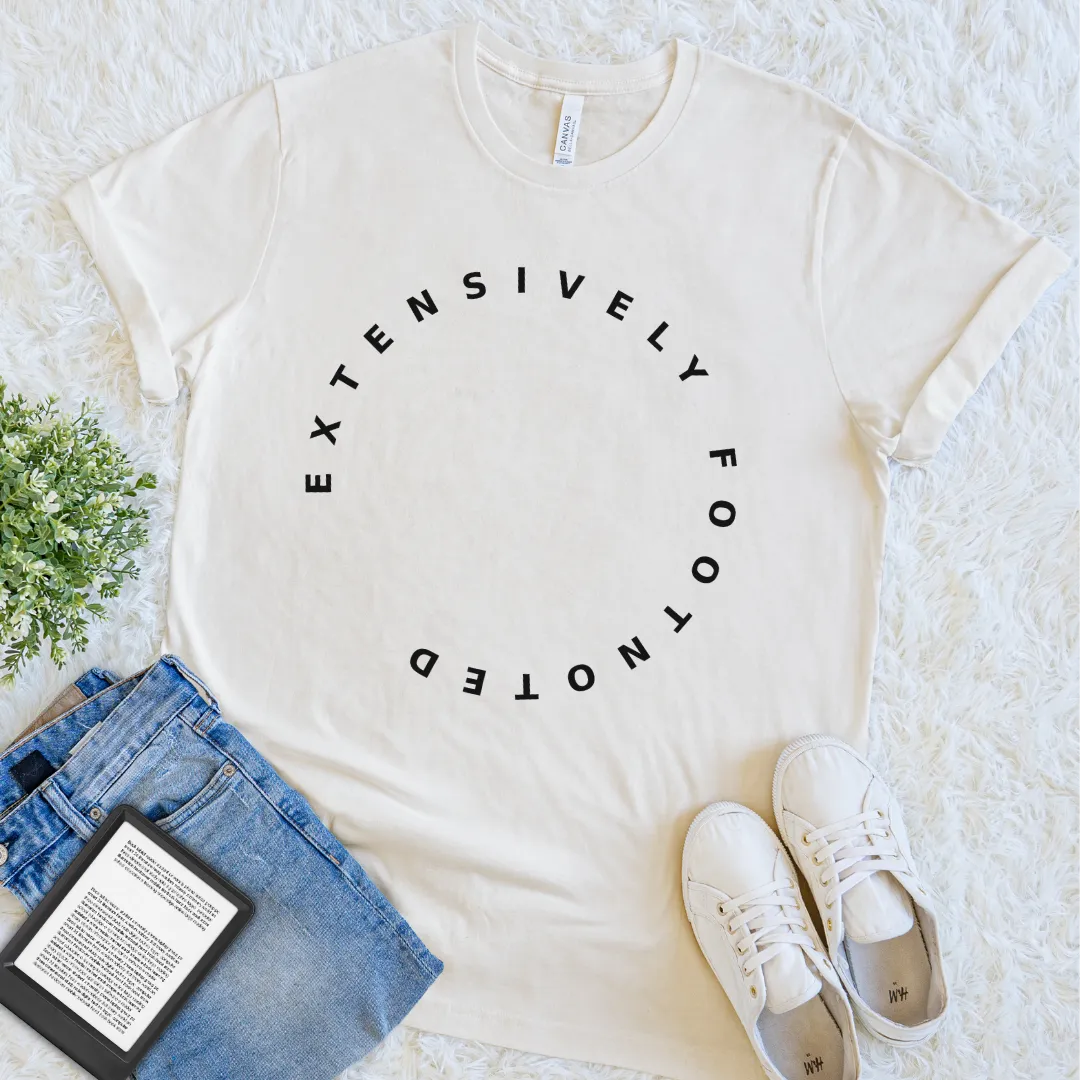 Natural “Extensively Footnoted” reader T-shirt with black circular typography, a minimalist book lover graphic tee for writers, researchers, and well-read minds.