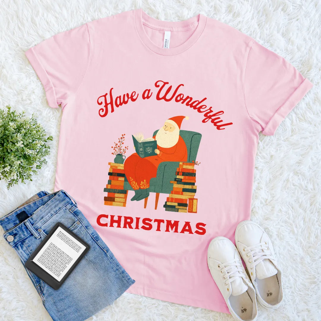 Santa reading a book in an armchair surrounded by stacks of books on pink shirt