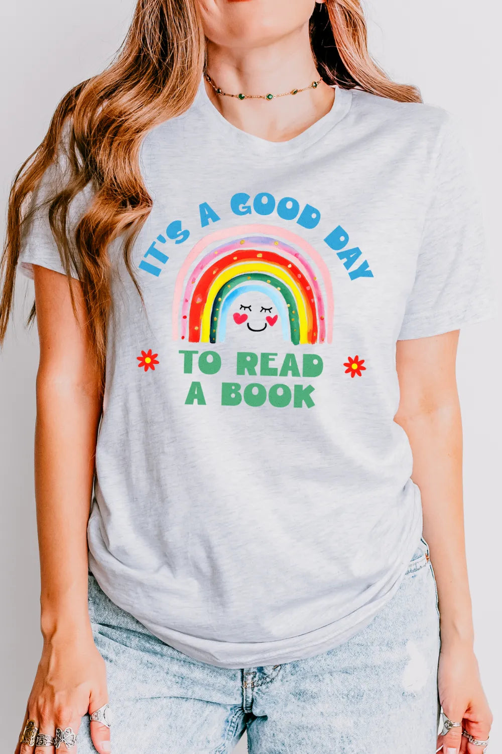 woman wearing soft cotton T-shirt featuring “It’s a good day to read a book” quote and happy rainbow