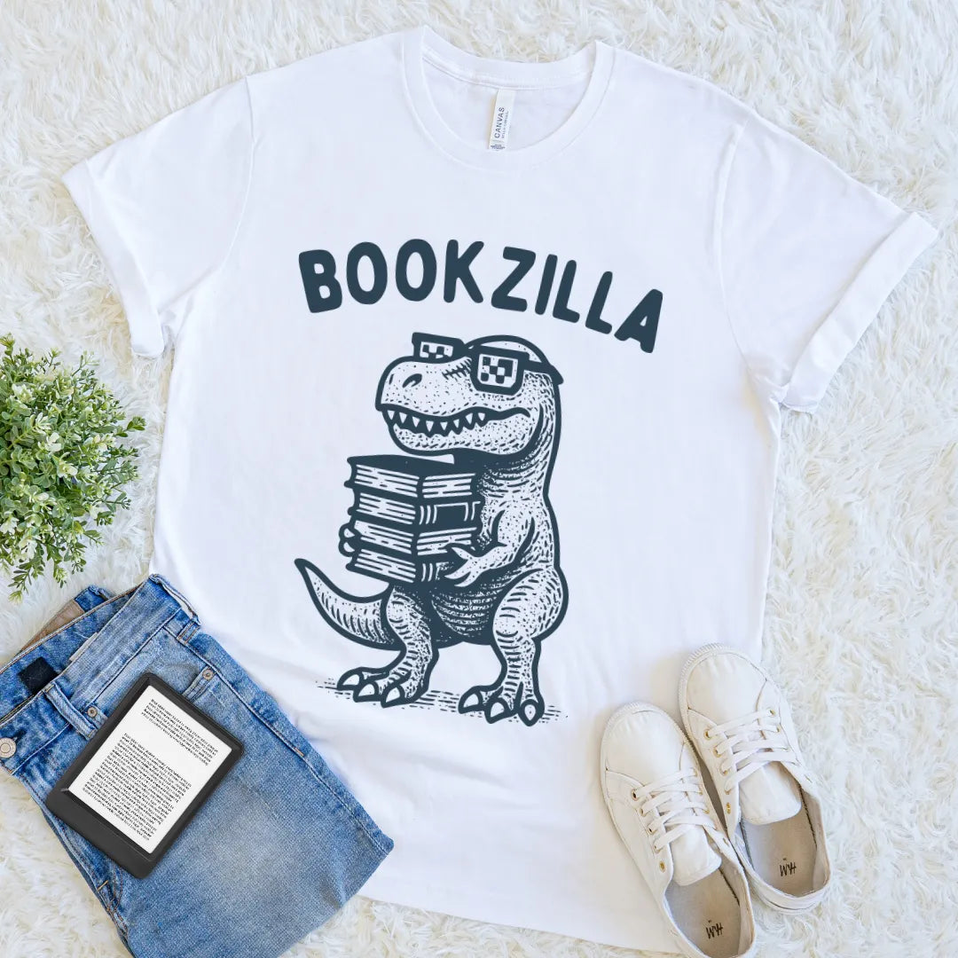White T-shirt with a cartoon T-rex holding books and wearing pixel glasses