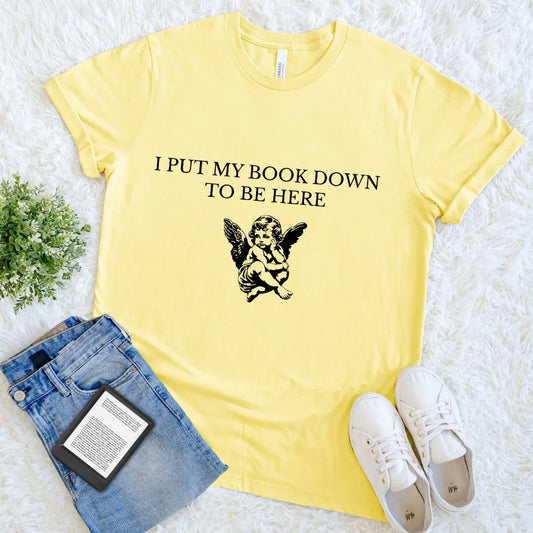 Flat lay of yellow soft cotton aesthetic literary tee styled with introvert quote with jeans and e-reader