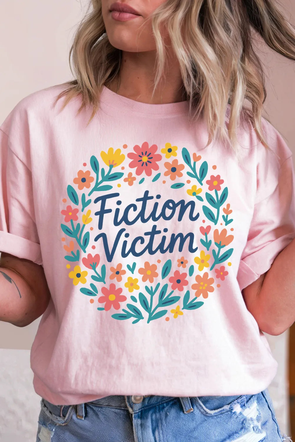woman wearing a pink soft cotton t-shirt with 'Fiction Victim' quote and floral design