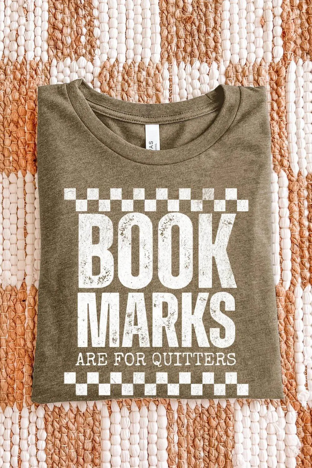 heather olive T-shirt with bold white distressed text โBookmarks Are for Quittersโ and checkered design