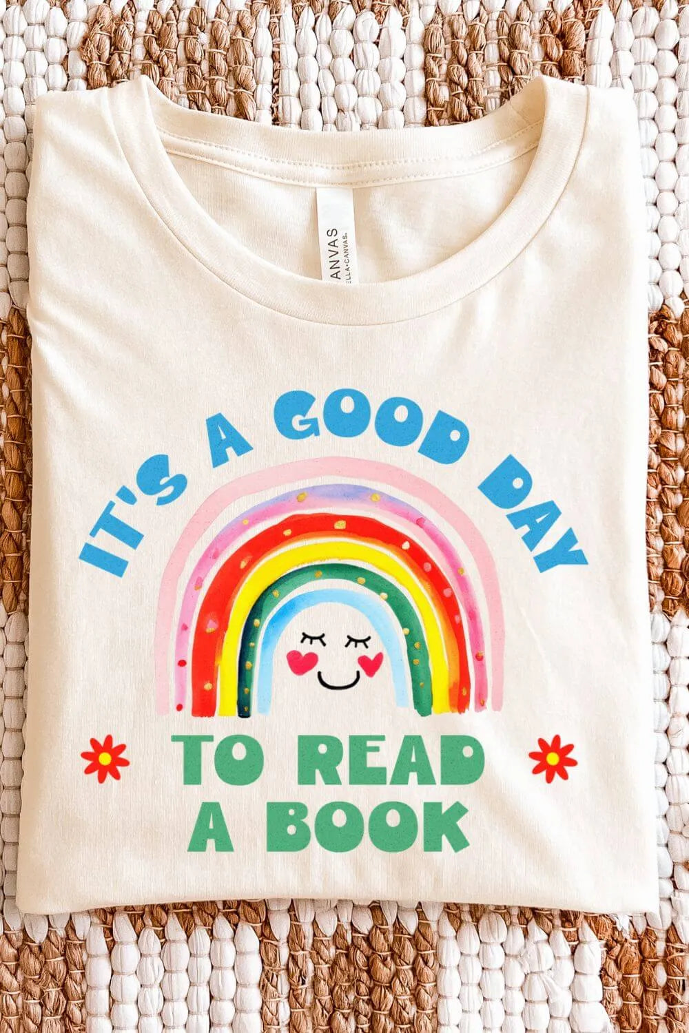 Soft cotton natural beige graphic t-shirt with a colorful rainbow illustration and the quote “It’s a Good Day to Read a Book,” styled in a cheerful bookish design.