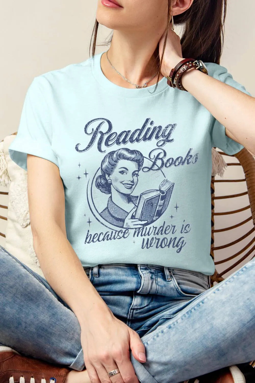 woman wearing heather Ice blue t-shirt with vintage design and “Reading Books Because Murder is Wrong” text styled with denim