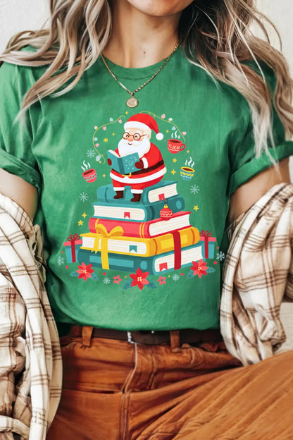 woman wearing green cozy holiday T-shirt with Santa reading on pile of books graphic