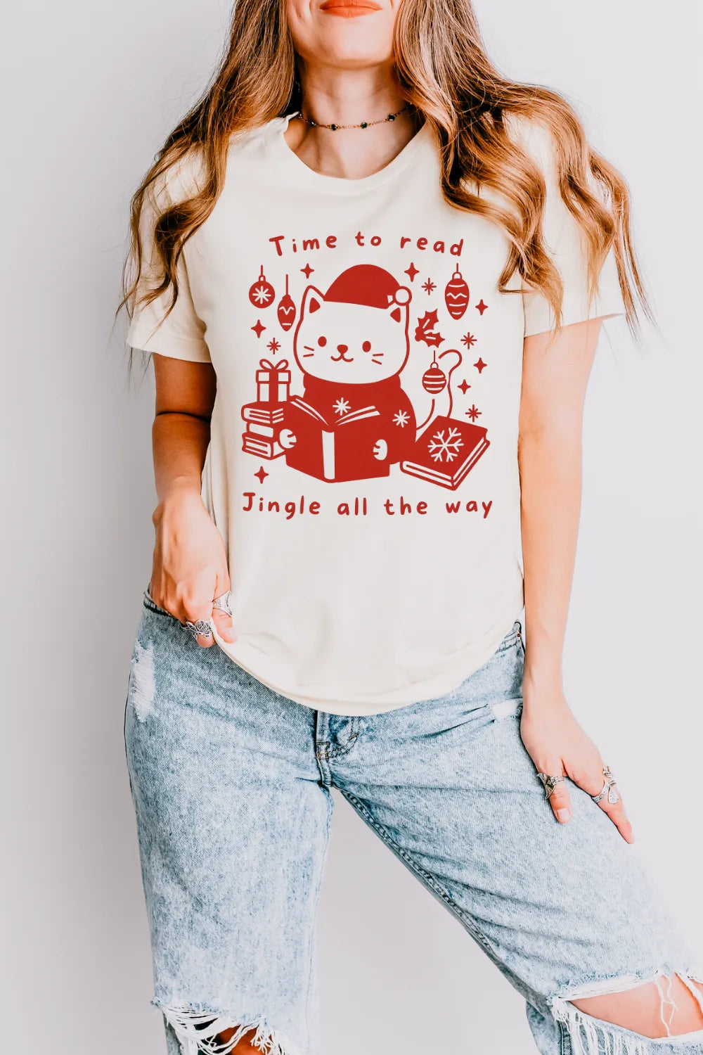 woman wearing Cozy literary Christmas t shirt with red print featuring cat and books