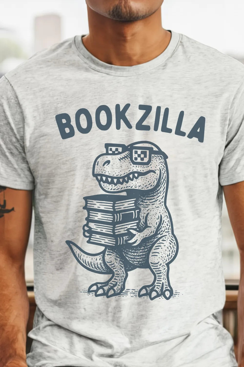 Person wearing a t-shirt with a dinosaur holding books graphic and 'BOOKZILLA' text.