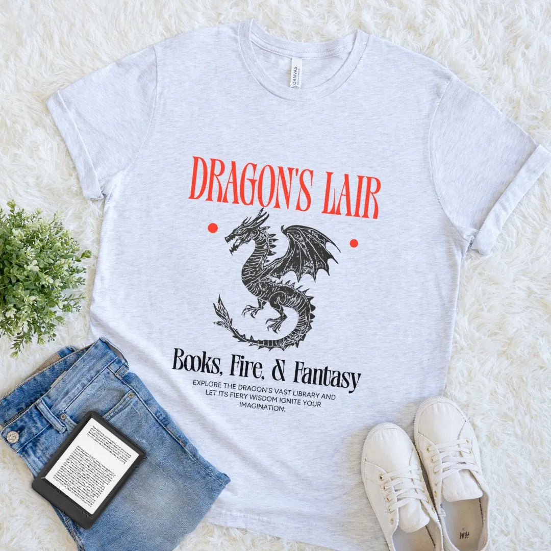 ash grey bookish  t-shirt with dragon graphic and text on a white surface with jeans and sneakers.