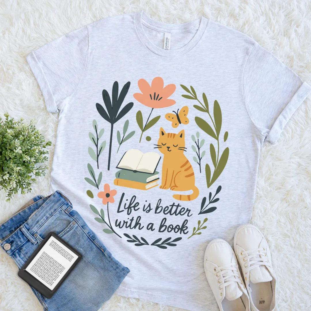 flat lay of ash grey  soft cotton t-shirt with cottagecore cat design and "life is better with a book" quote   