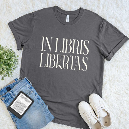 Dark academia aesthetic graphic tee styled with books and casual denim outfit featuring elegant “In Libris Libertas” Latin typography for book lovers