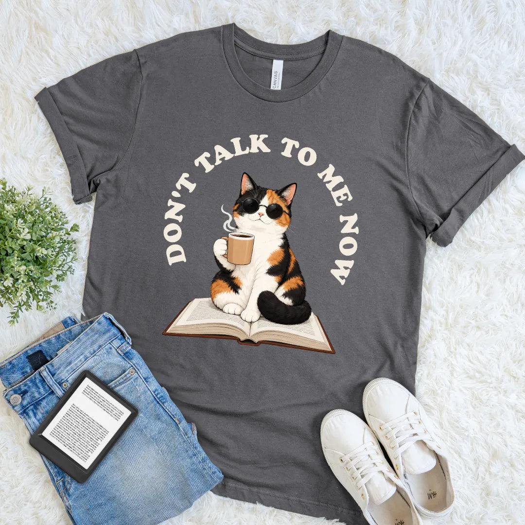 Asphalt reading cat T-shirt with a sunglasses-wearing calico, open book, coffee mug, and “Don’t Talk to Me Now” slogan