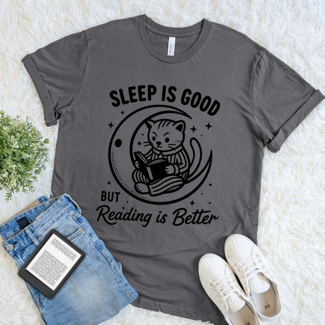 Charcoal bookish T-shirt with a reading cat on a crescent moon and Sleep Is Good but Reading Is Better quote.