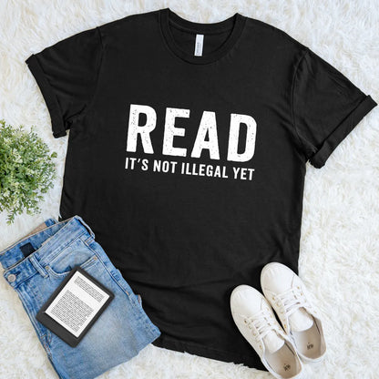 Black T-shirt with bold white text saying “Read It’s Not Illegal Yet”