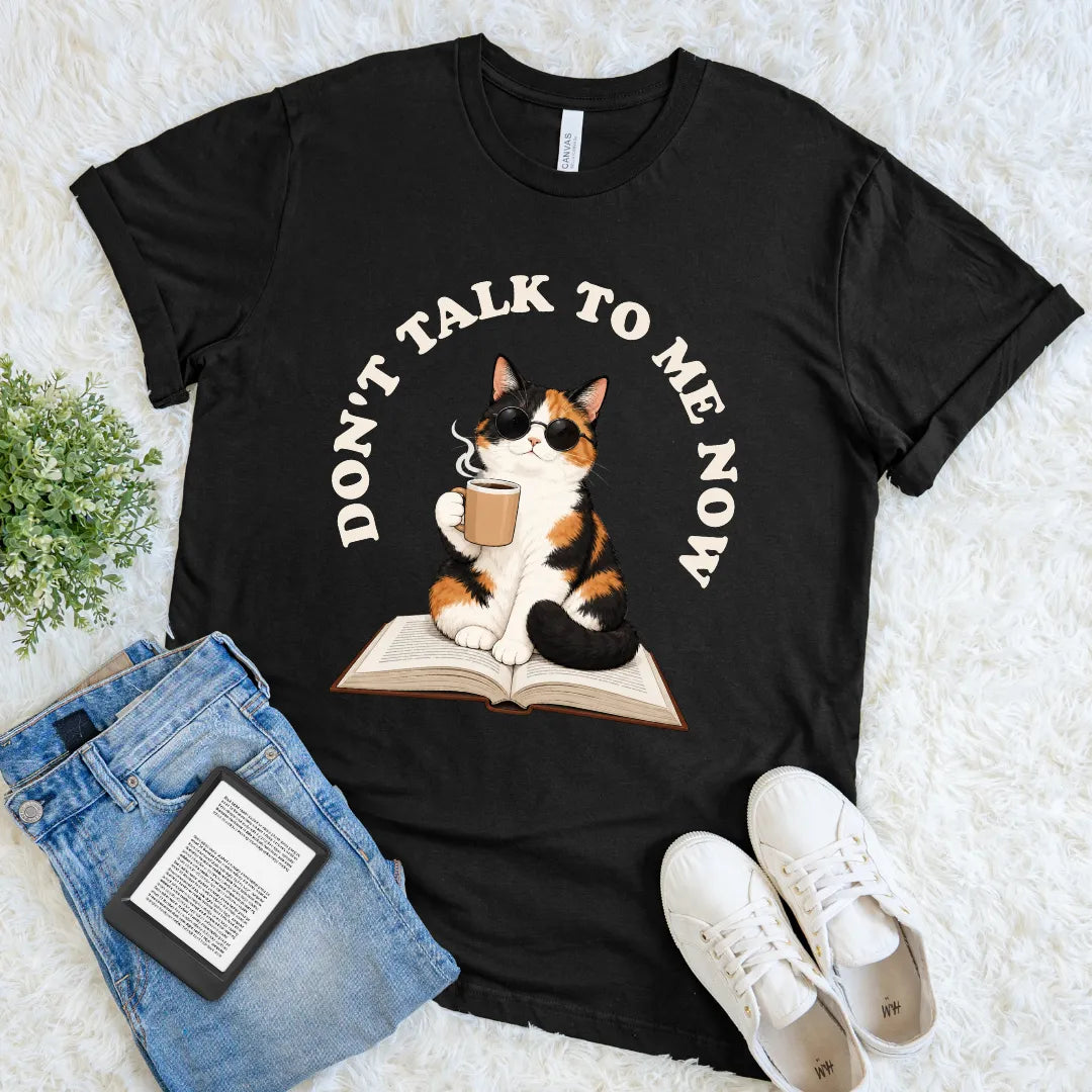 Black funny cat and book lover tee featuring an unbothered calico reader with steaming coffee and playful typography