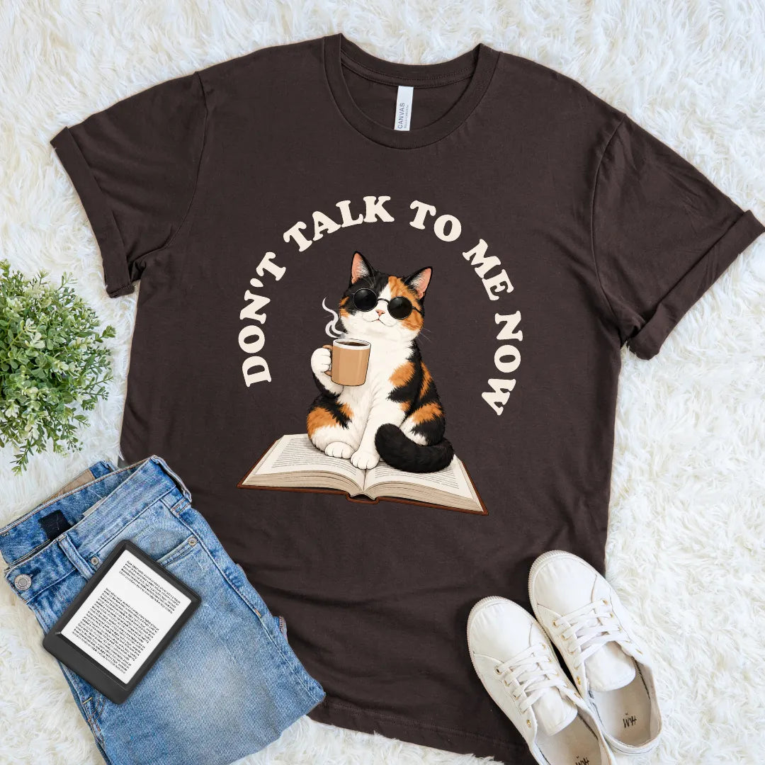 Brown cozy reader T-shirt showing a coffee-drinking calico cat in sunglasses for peaceful reading days without interruptions