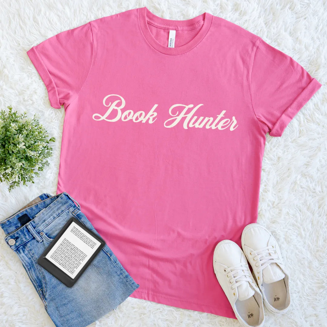 Aesthetic literary shirt with Book Hunter phrase in vintage font on bright pink cotton 