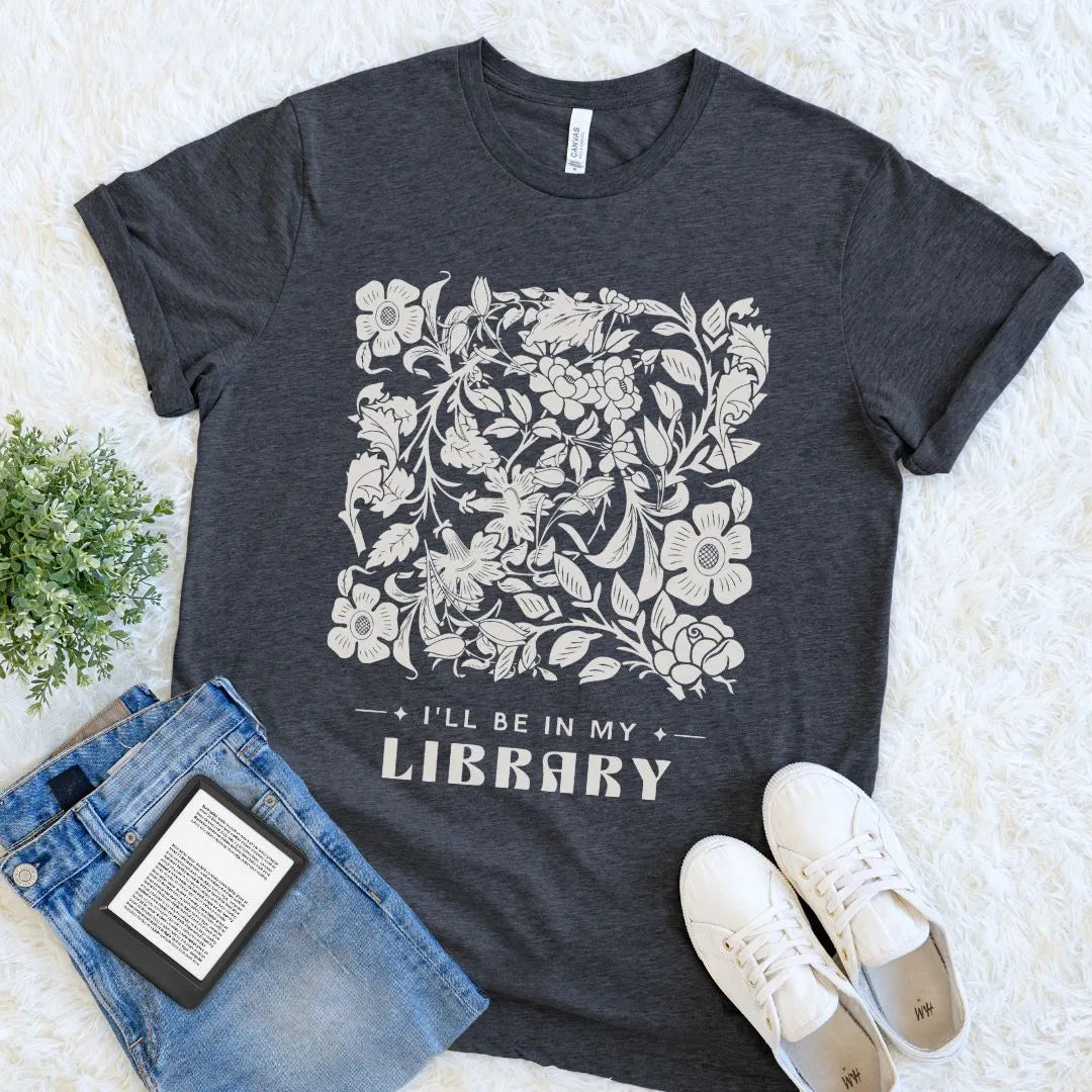 Dark gray heather t-shirt with floral design and text 'I'll be in my library' on a light background