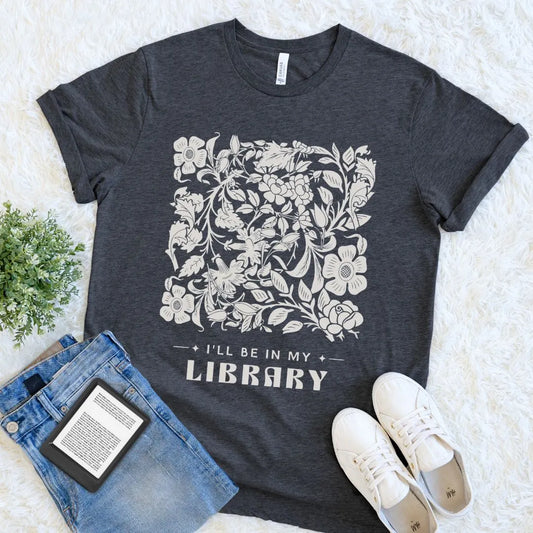 Dark Grey Heather “I’ll Be in My Library” T-shirt with a delicate floral design, a book lover graphic tee for readers, bibliophiles, and quiet library-centered style.