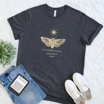 Soft dark grey heather t-shirt ro readers featuring latin  quote "we read in dark" in golden typography  and vintage moth with  stars design 