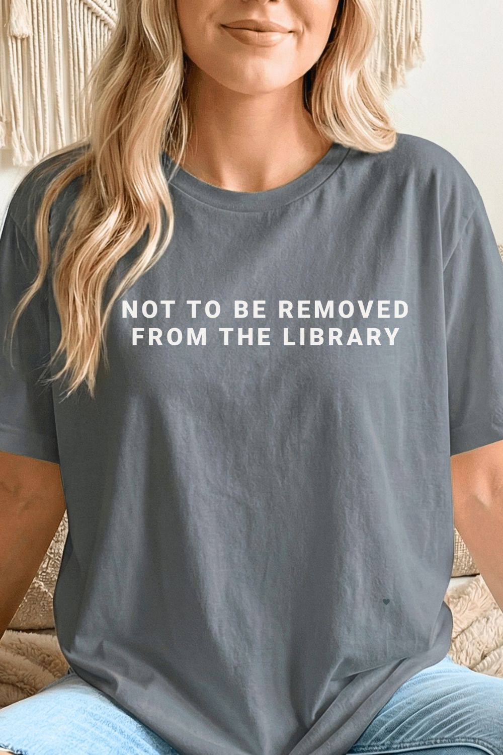 woman wearing a gray bookish t-shirt with text 'NOT TO BE REMOVED FROM THE LIBRARY' styled with jeans for cozy reading outfit