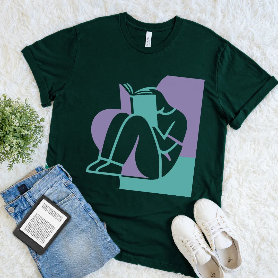 Forest green Lost In A Book reader T-shirt featuring teal and lavender geometric artwork of a person absorbed in reading, a modern bookish graphic tee.
