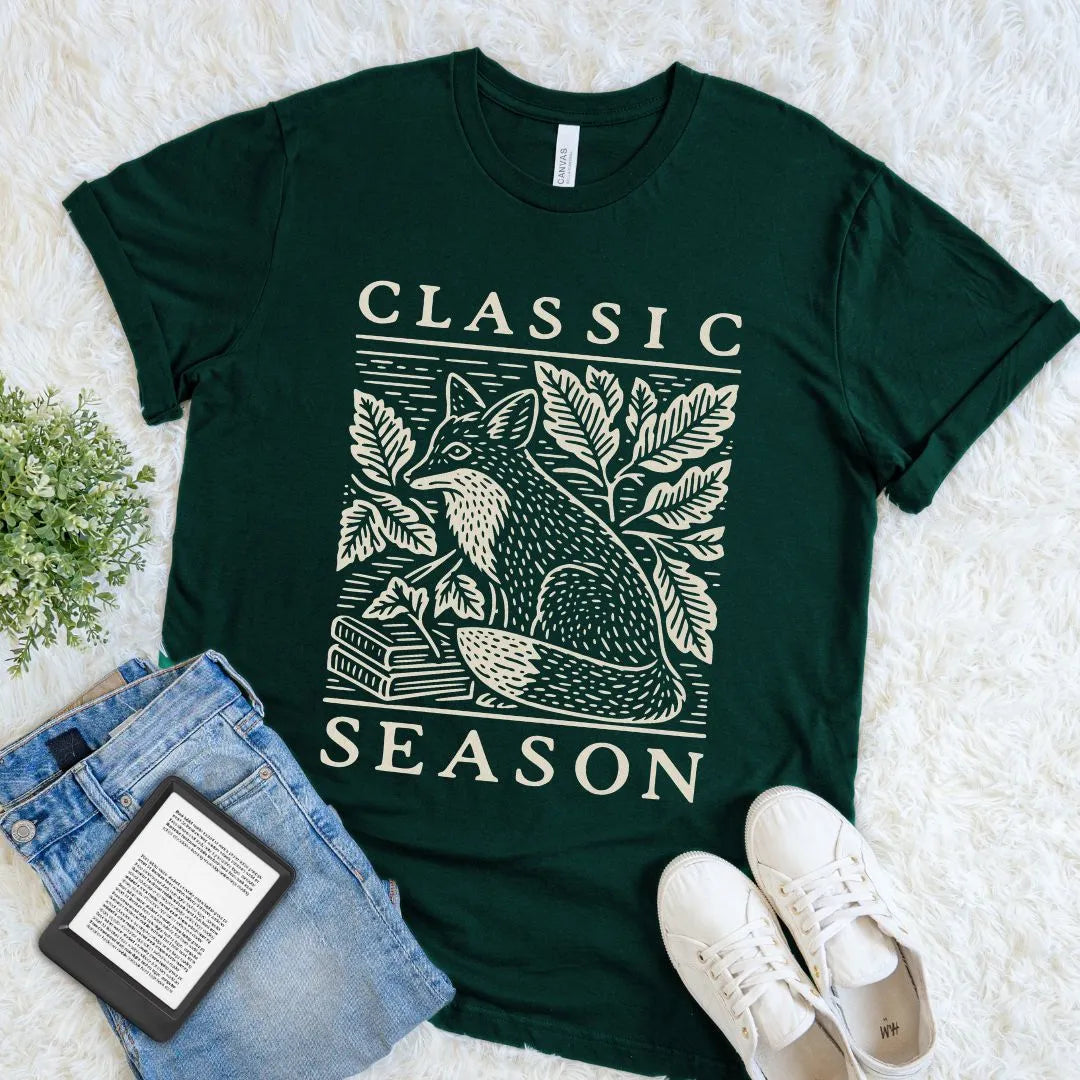 Forest green book lover tee with a watchful fox beside classic novels in an old-fashioned woodland engraving