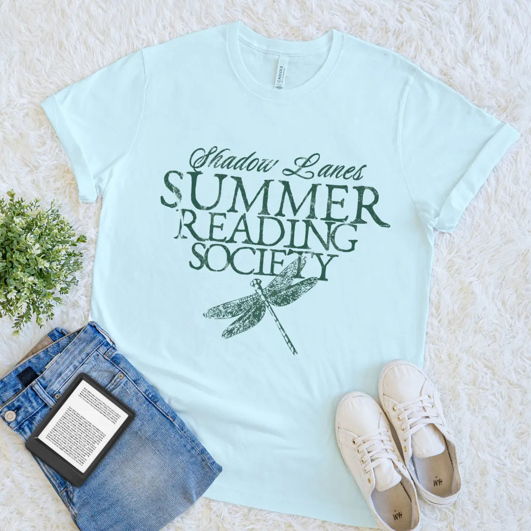 Heather ice blue minimalist bookish tee with green text and dragonfly artwork on neutral fabric
