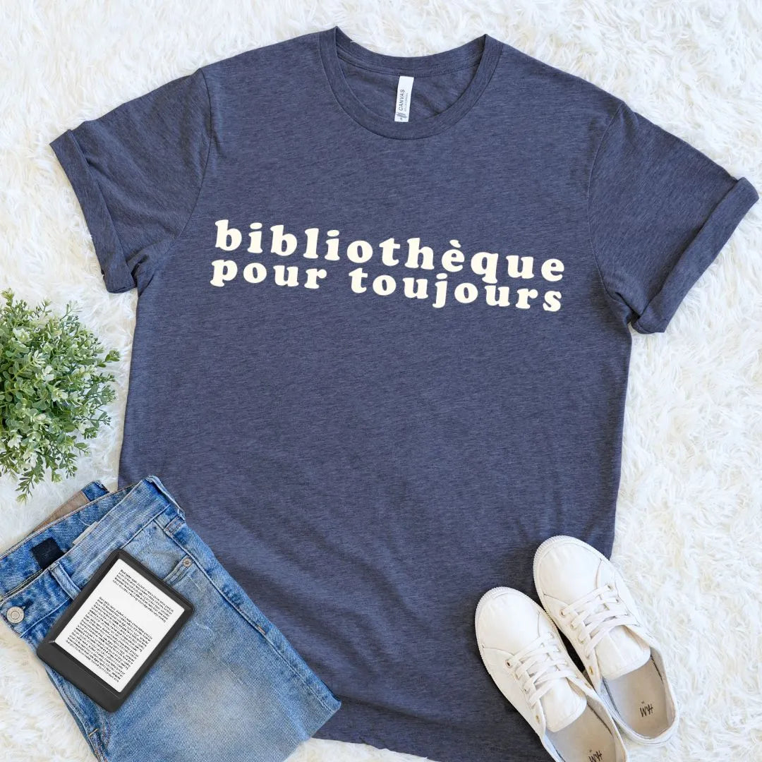 Heather navy French library lover shirt featuring cream retro lettering, arranged with denim, sneakers, and a digital book