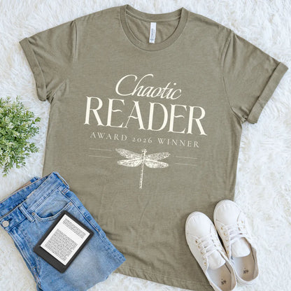 Flat lay of reader heather olive shirt with chaotic reader text, jeans, sneakers, and ebook