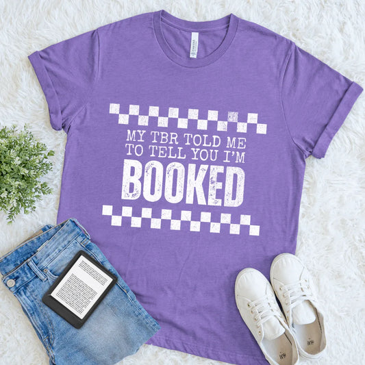 Flat lay of funny reader shirt with checkered accents and humorous quote for introverts in heather team purple