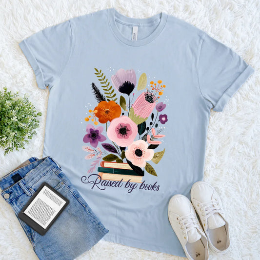 Raised by Books text with stacked books and flowers graphic t-shirt in light blue 