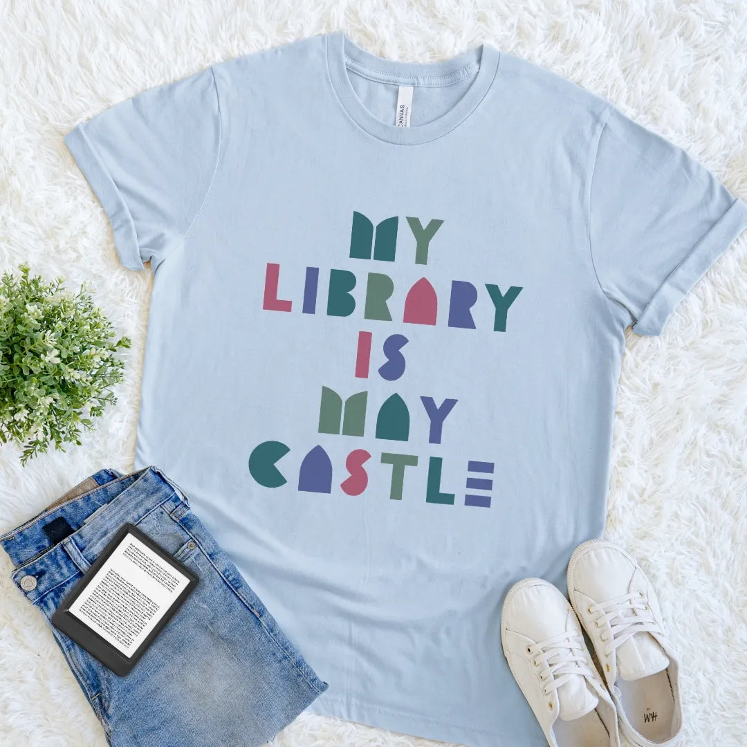 Light blue bookish T-shirt with colorful My Library Is My Castle typography and playful geometric letters.