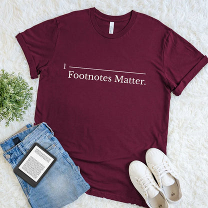 Minimalist academic humor apparel with Footnotes Matter slogan on maroon red cotton