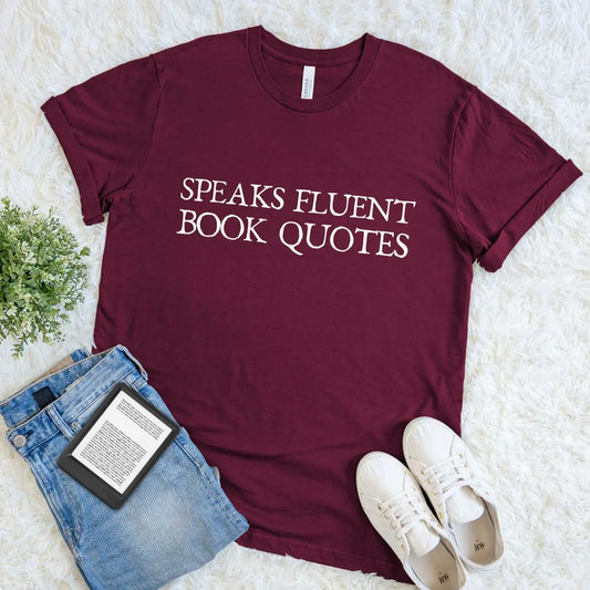 soft cotton maroon red  t-shirt with 'Speaks Fluent Book Quotes' text, paired with jeans and sneakers on a light background