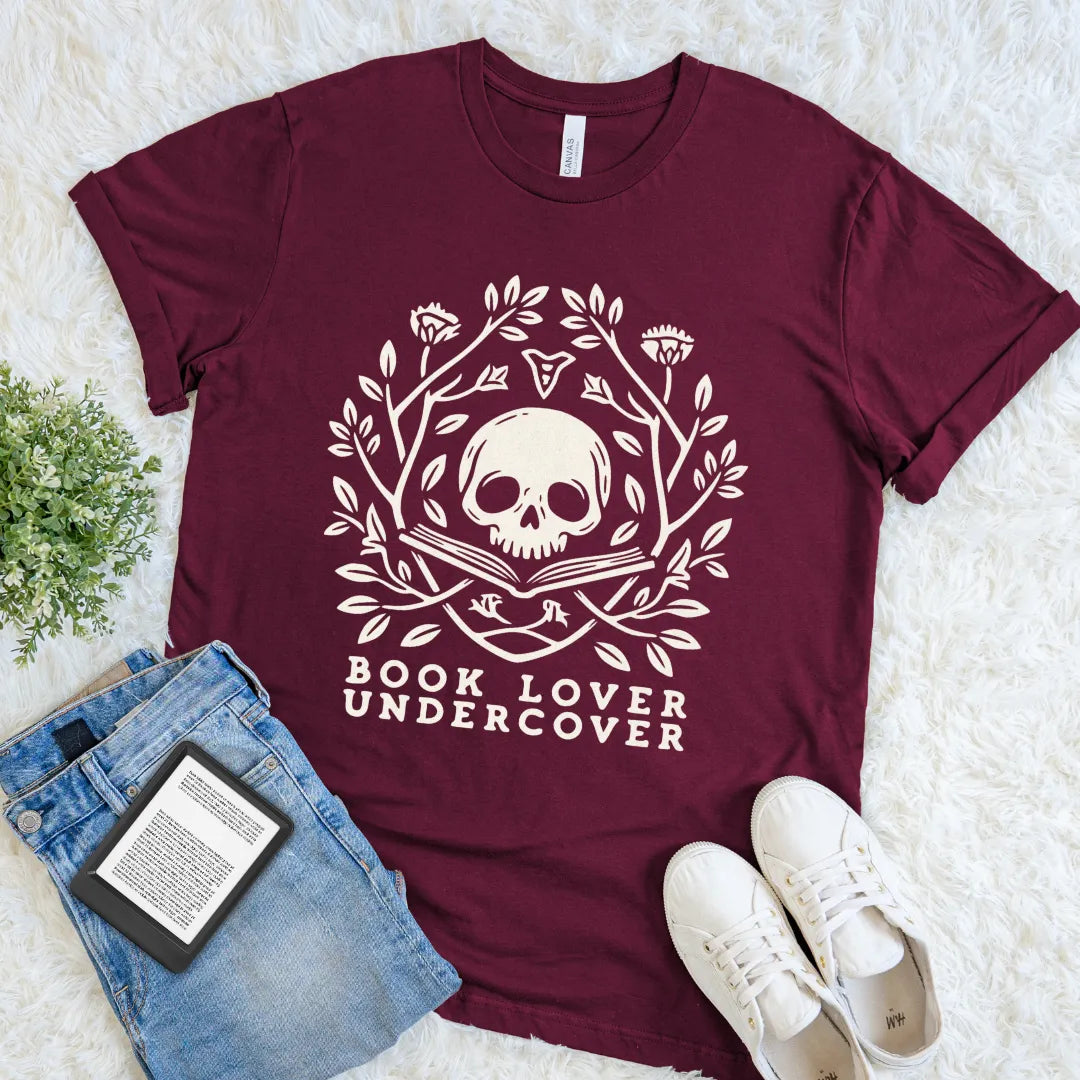 Maroon literary T-shirt pairing Book Lover Undercover lettering with an illustrated skull emerging from an open book