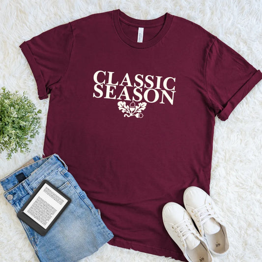 Maroon Classic Season bookish T-shirt featuring vintage cream typography with oak leaves and acorns, a fall reading tee for lovers of literary classics.