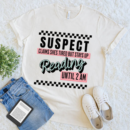 flat lay of cream soft cotton pastel checkered t-shirt featuring "suspect reading until 2am" bookish quote 
