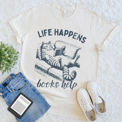 Cream T-shirt with lounging cat reading on a sofa and “Life Happens Books Help” quote