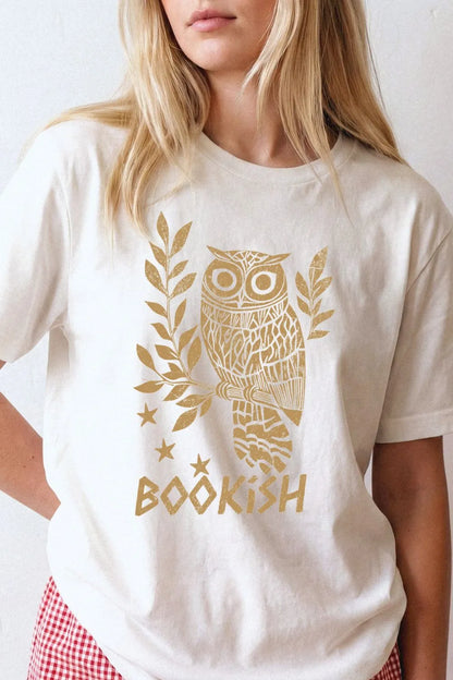 woman wearing a white reader t-shirt with a gold owl design and 'BOOKISH' text styled in relaxed academia look